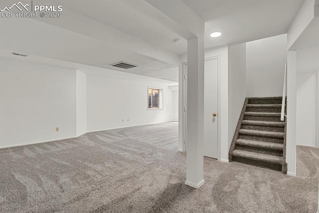 Image 33 of 50: Spacious room featuring light gray carpeting, neutral white walls, and a vi