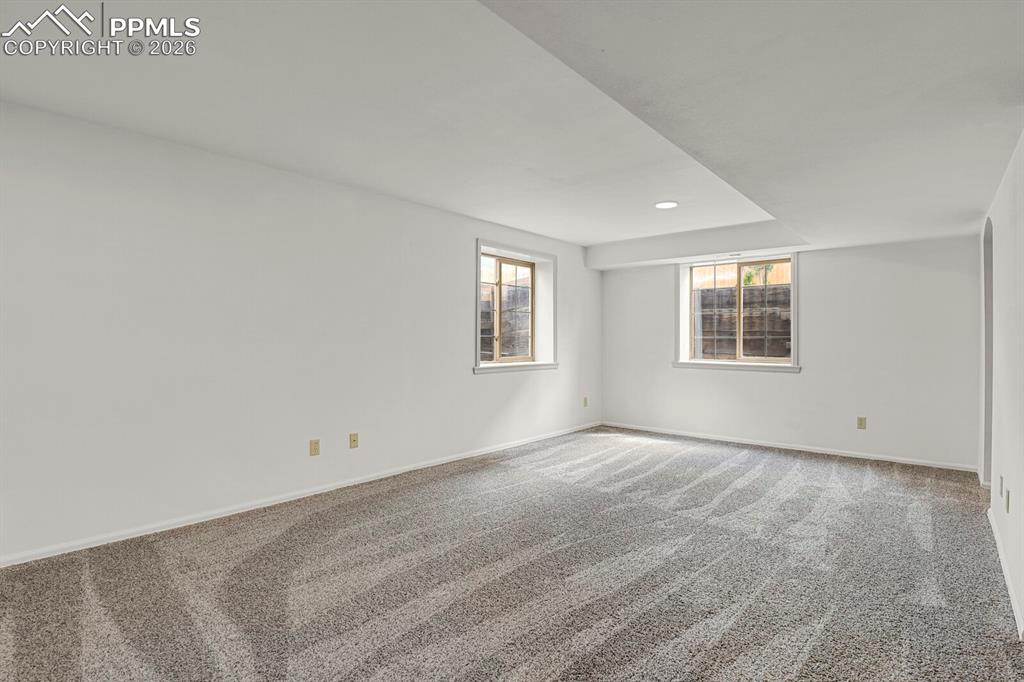 Image 34 of 50: Spacious room featuring light-colored walls, recessed lighting, and two win