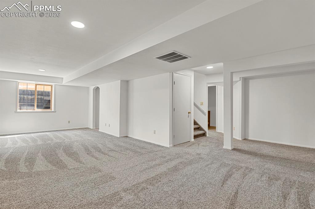 Image 35 of 50: Spacious room featuring light gray carpeting, recessed lighting, and a wind