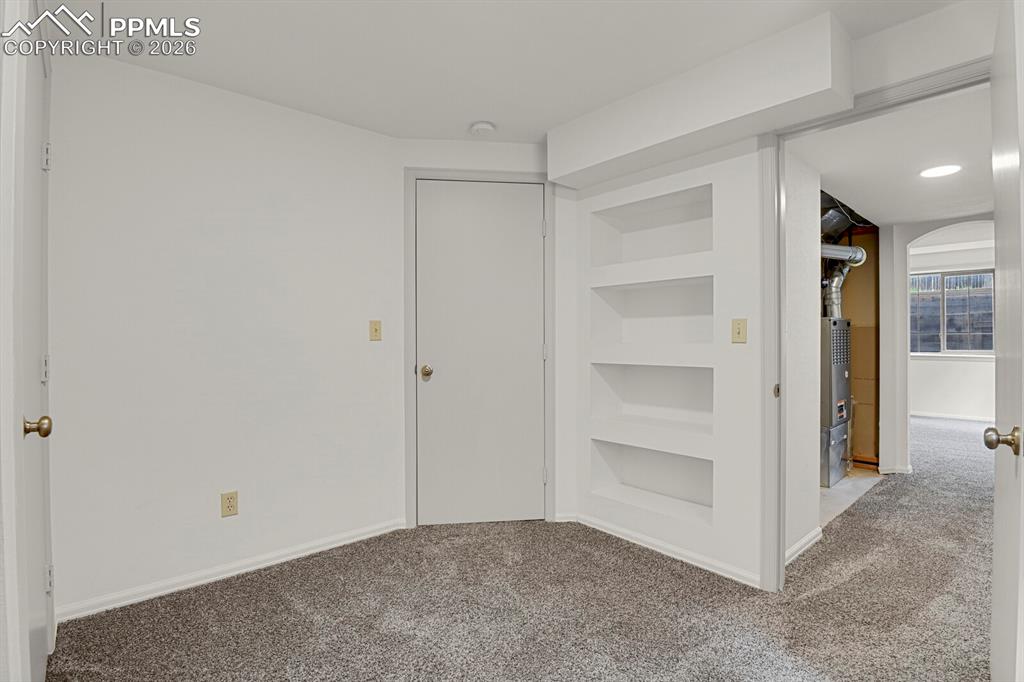 Image 38 of 50: Room featuring light gray carpet, white walls, and built-in shelving
