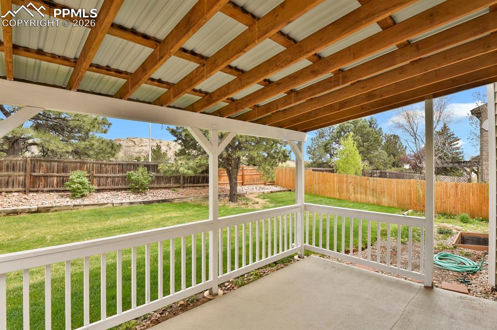 Image 42 of 50: The property features a covered patio with a concrete floor, white railing,