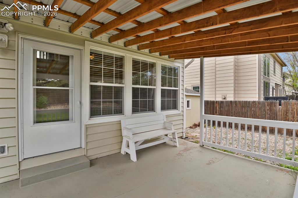 Image 43 of 50: Covered porch area featuring a concrete floor, a white railing, and a white