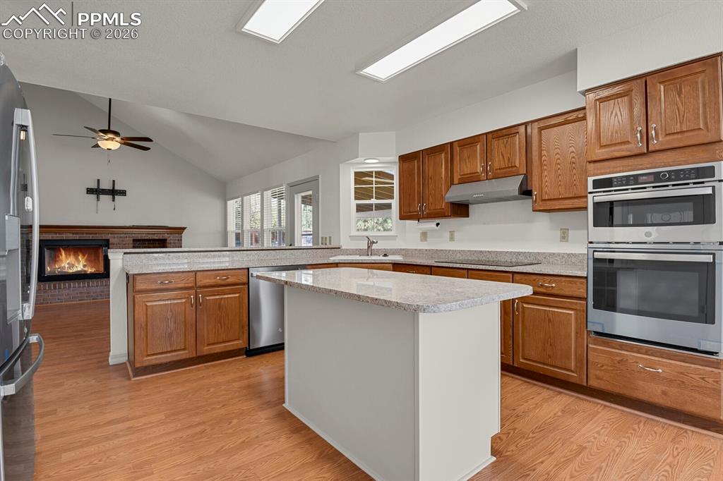 Image 9 of 50: This open-concept kitchen features wood cabinetry, stainless steel applianc
