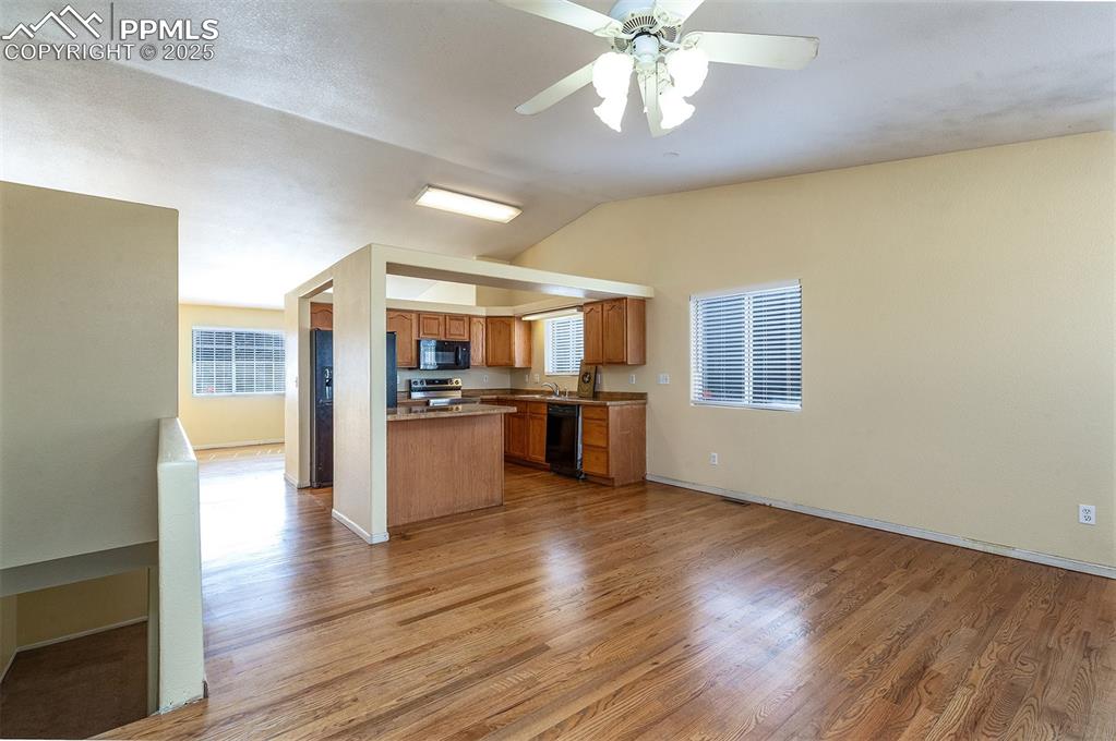 Image 10 of 31: Kitchen with brown cabinetry, black appliances, light wood-type flooring, a
