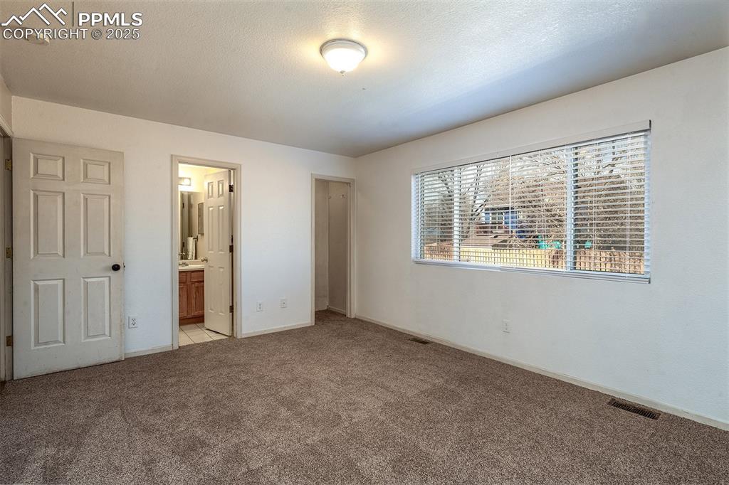Image 14 of 31: Unfurnished bedroom with light carpet, visible vents, a textured ceiling, a