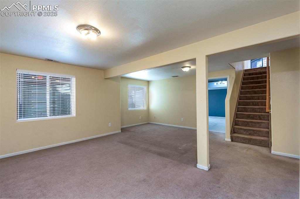 Image 17 of 31: Below grade area with baseboards, visible vents, stairs, a textured ceiling