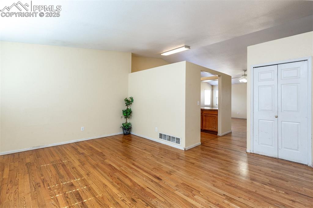 Image 2 of 31: Empty room featuring visible vents, baseboards, lofted ceiling, light wood-