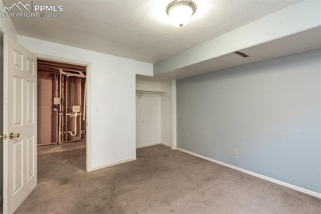 Image 23 of 31: Unfurnished bedroom featuring carpet, baseboards, a closet, and a textured 