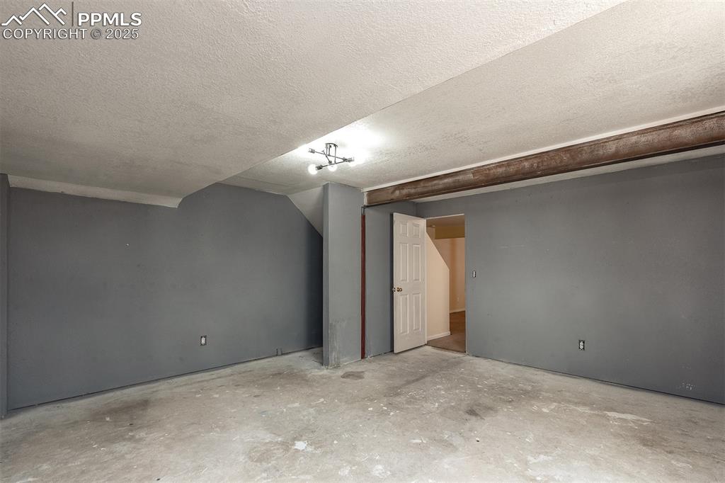 Image 25 of 31: Bonus room featuring unfinished concrete flooring and a textured ceiling