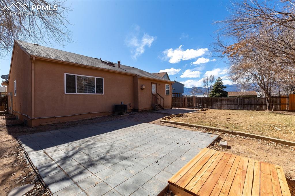 Image 28 of 31: Rear view of house with stucco siding, cooling unit, and fence private yard