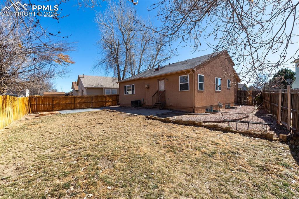 Image 29 of 31: Rear view of house featuring a patio, cooling unit, a fenced backyard, stuc