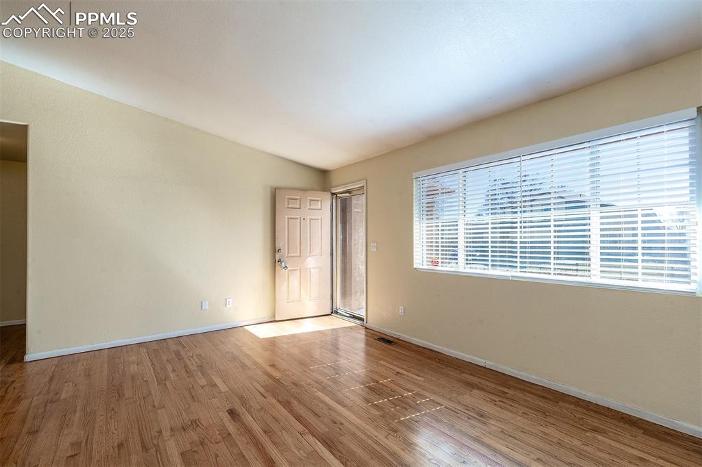 Image 4 of 31: Spare room featuring lofted ceiling, wood finished floors, baseboards, and 