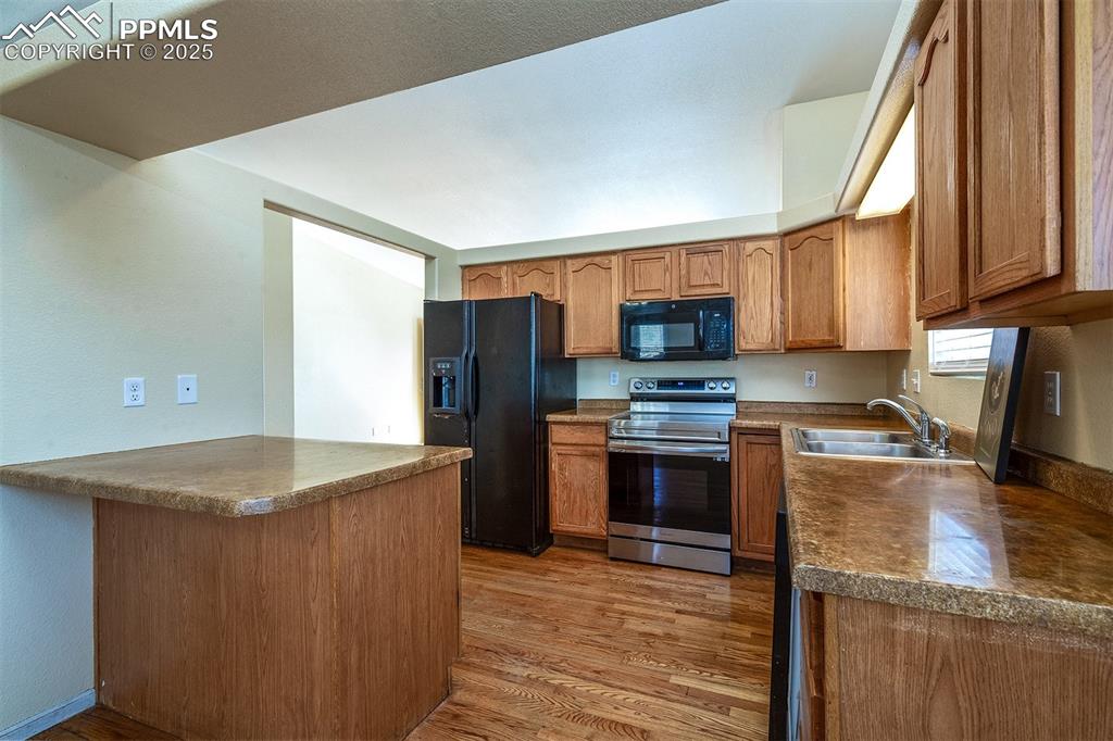 Image 7 of 31: Kitchen with dark countertops, light wood-type flooring, brown cabinetry, b