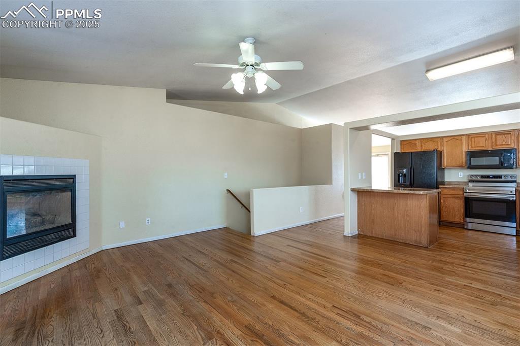 Image 9 of 31: Kitchen with open floor plan, vaulted ceiling, wood finished floors, brown 