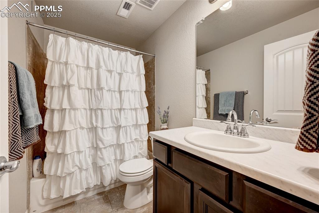 Image 40 of 50: Bathroom featuring visible vents, toilet, vanity, and a textured ceiling