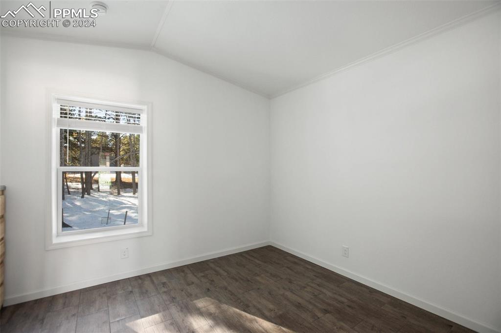 Image 5 of 15: Unfurnished room with lofted ceiling, dark wood-type flooring, and ornament