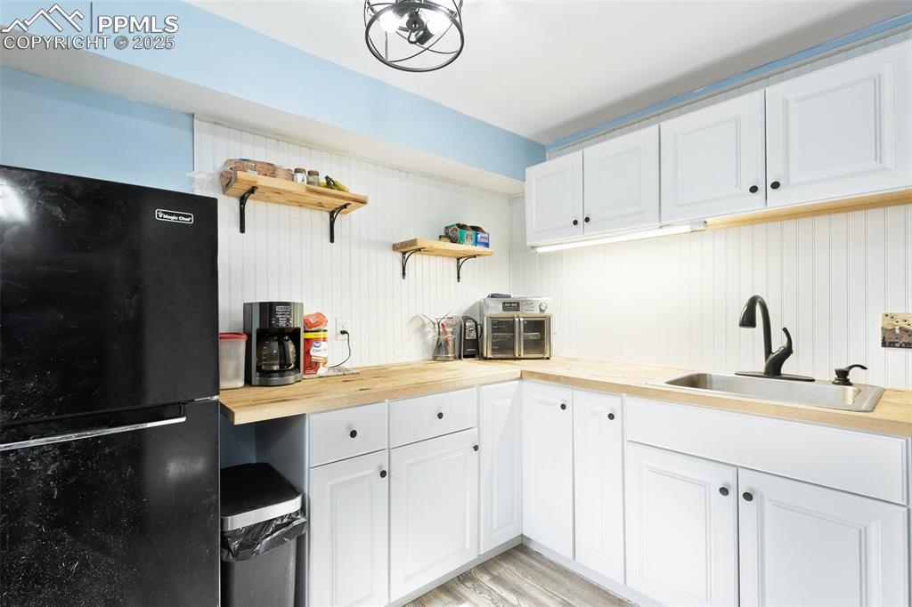 Image 10 of 28: Kitchen with wooden counters, freestanding refrigerator, open shelves, and 