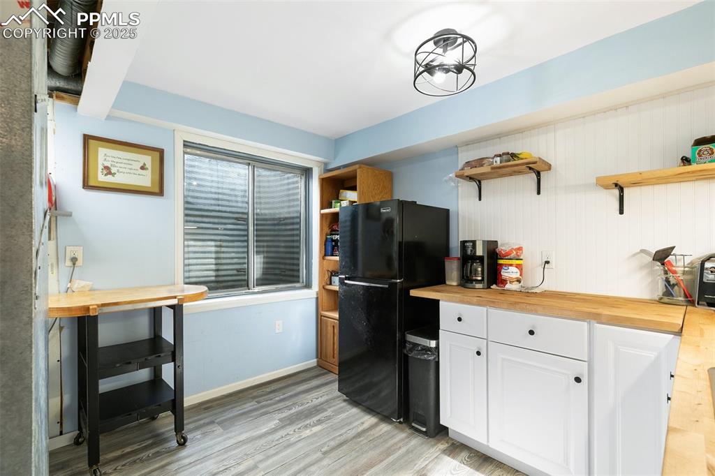 Image 11 of 28: Kitchen with open shelves, butcher block counters, light wood finished floo