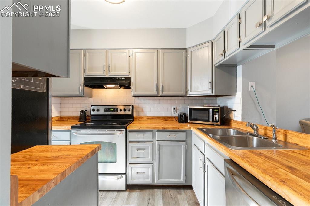 Image 12 of 28: Kitchen with butcher block counters, appliances with stainless steel finish