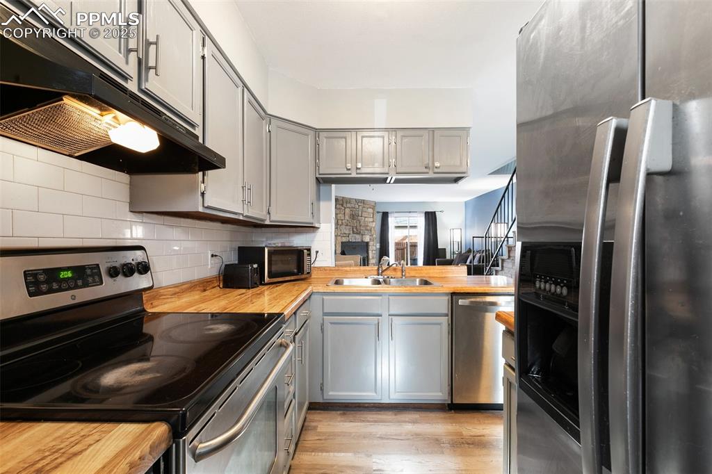 Image 13 of 28: Kitchen with stainless steel appliances, gray cabinets, under cabinet range