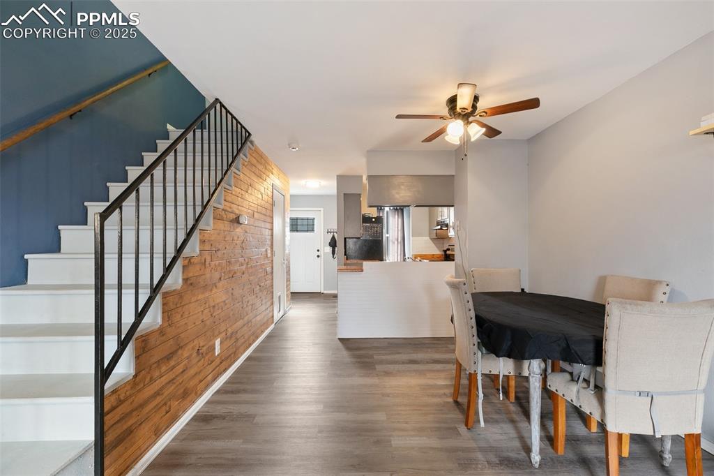 Image 16 of 28: Dining room featuring a ceiling fan, stairs, wood finished floors, and wood