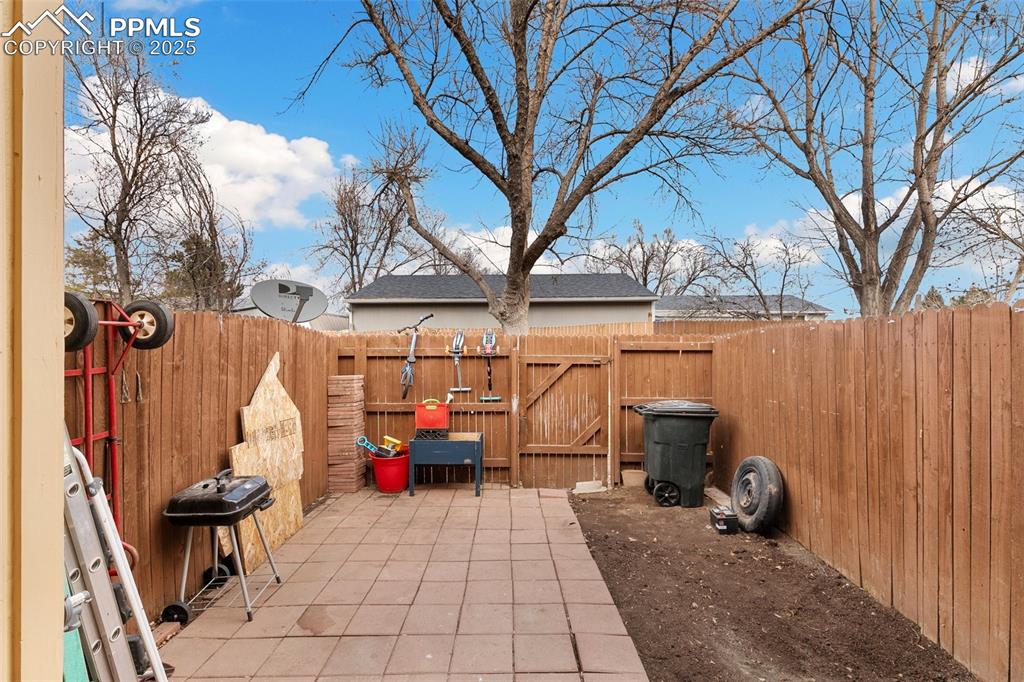 Image 28 of 28: Fenced backyard featuring a gate, a patio area, and grilling area