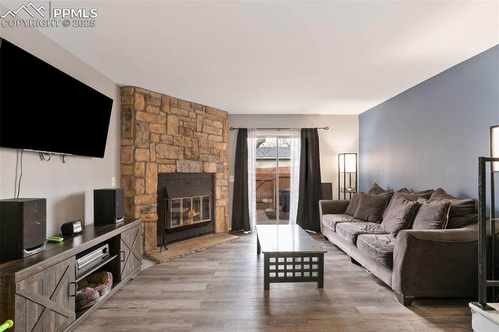 Image 6 of 28: Living area featuring a stone fireplace and wood finished floors