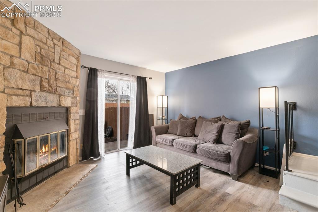 Image 8 of 28: Living area with wood finished floors and a stone fireplace