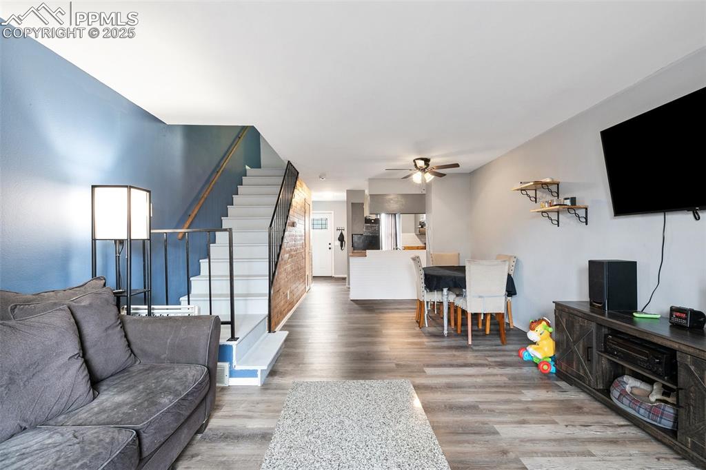 Image 9 of 28: Living area featuring stairs, wood finished floors, and a ceiling fan