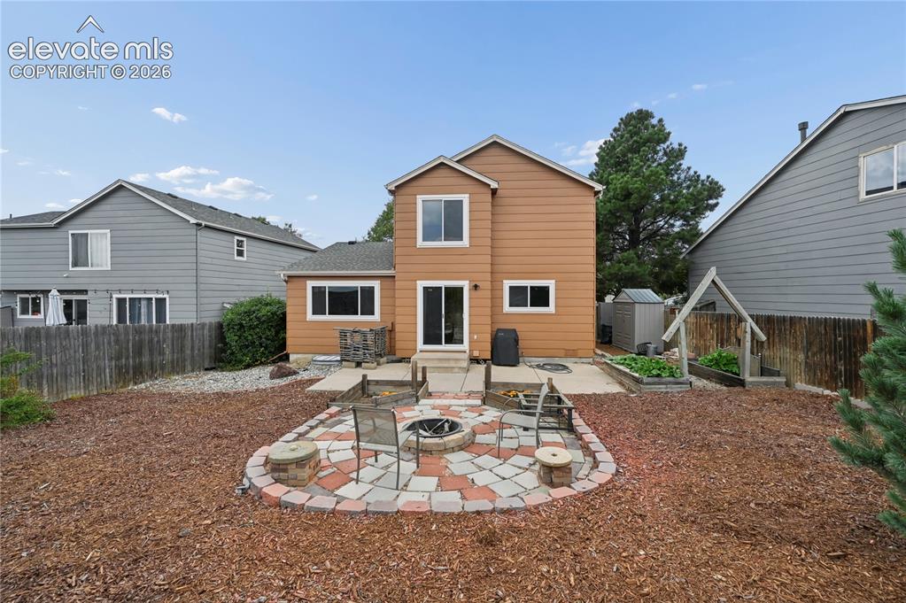 Image 12 of 41: Firepit patio and raised garden beds