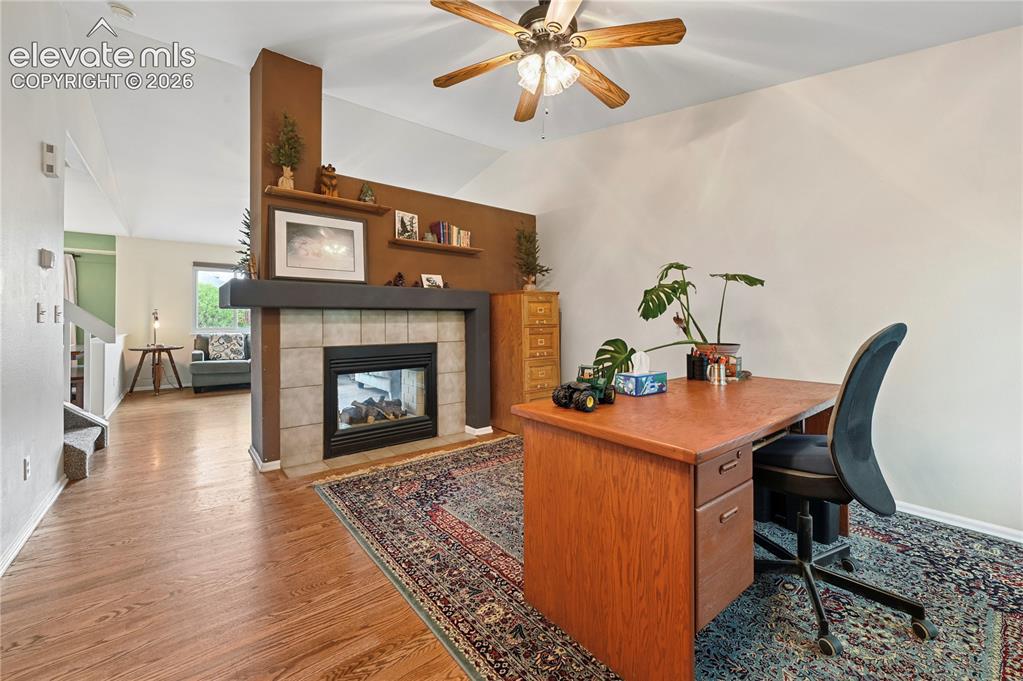 Image 3 of 41: Front room with solid-oak flooring, vaulted ceilings, and two-sided firepla