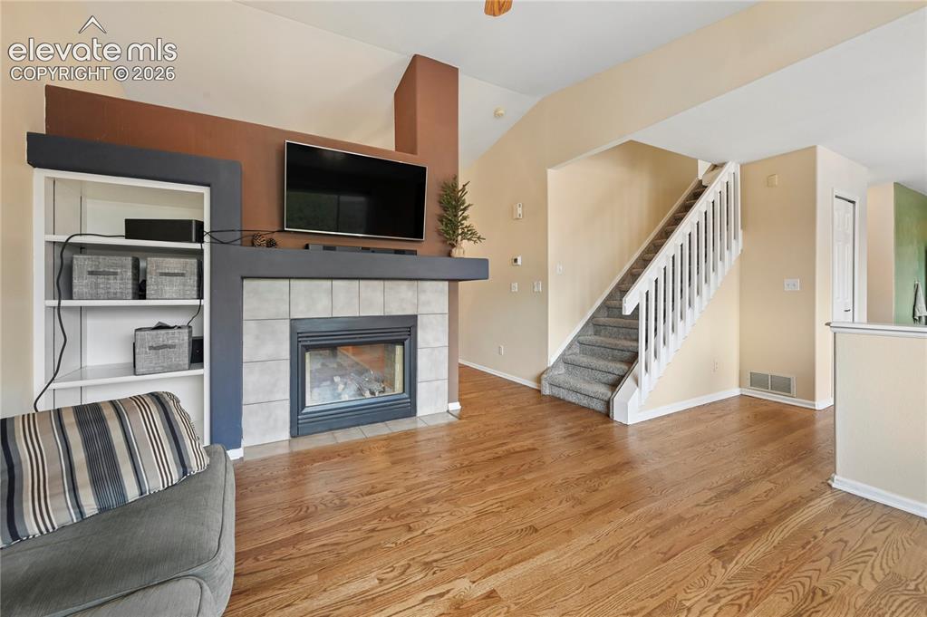 Image 5 of 41: Living room with solid-oak flooring, vaulted ceilings, two-sided fireplace,