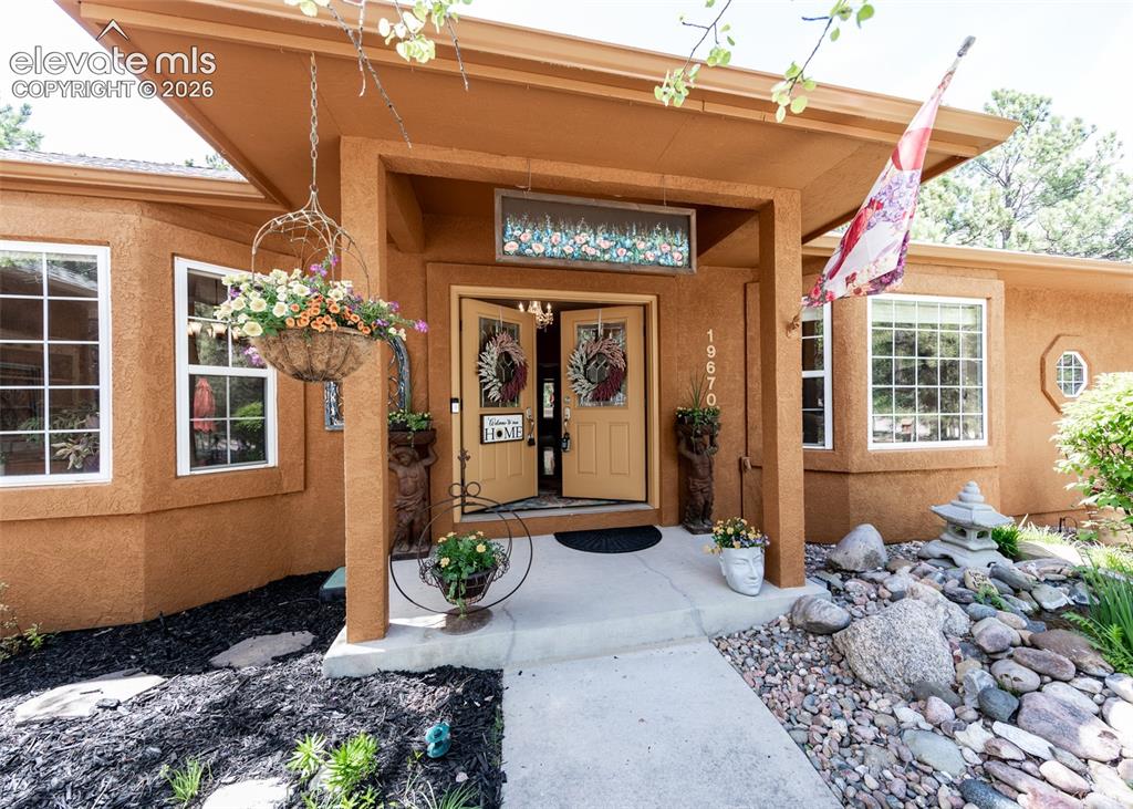 Image 10 of 50: Stucco exterior with a covered entry, double front doors, and a decorative