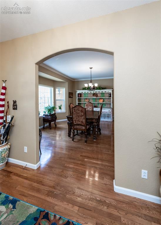 Image 15 of 50: Archway entry to a room featuring wood-finish flooring, a bay window, and c