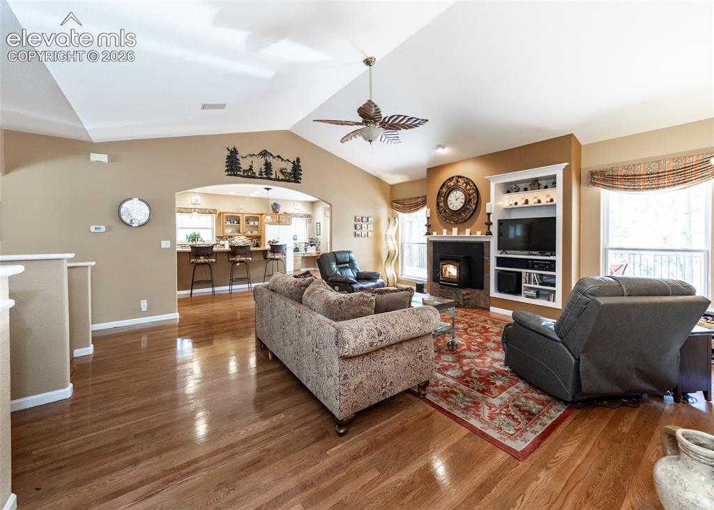 Image 18 of 50: Spacious living area featuring high vaulted ceilings, rich wood-finish floo