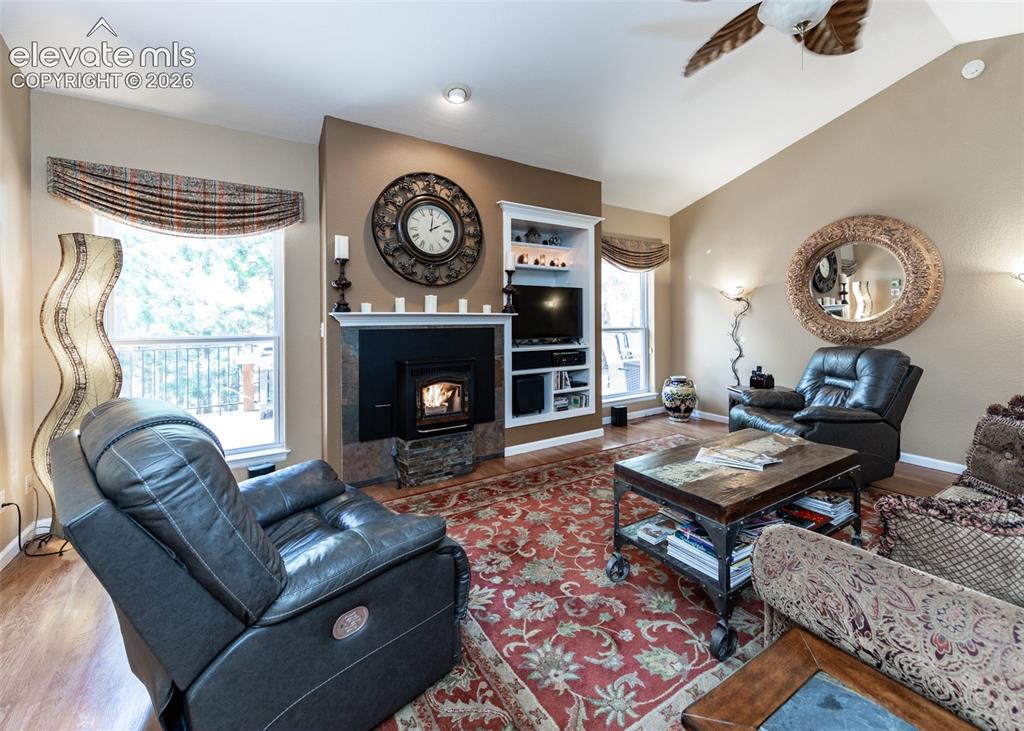 Image 19 of 50: Living area featuring a central fireplace with stone surround, built-in she