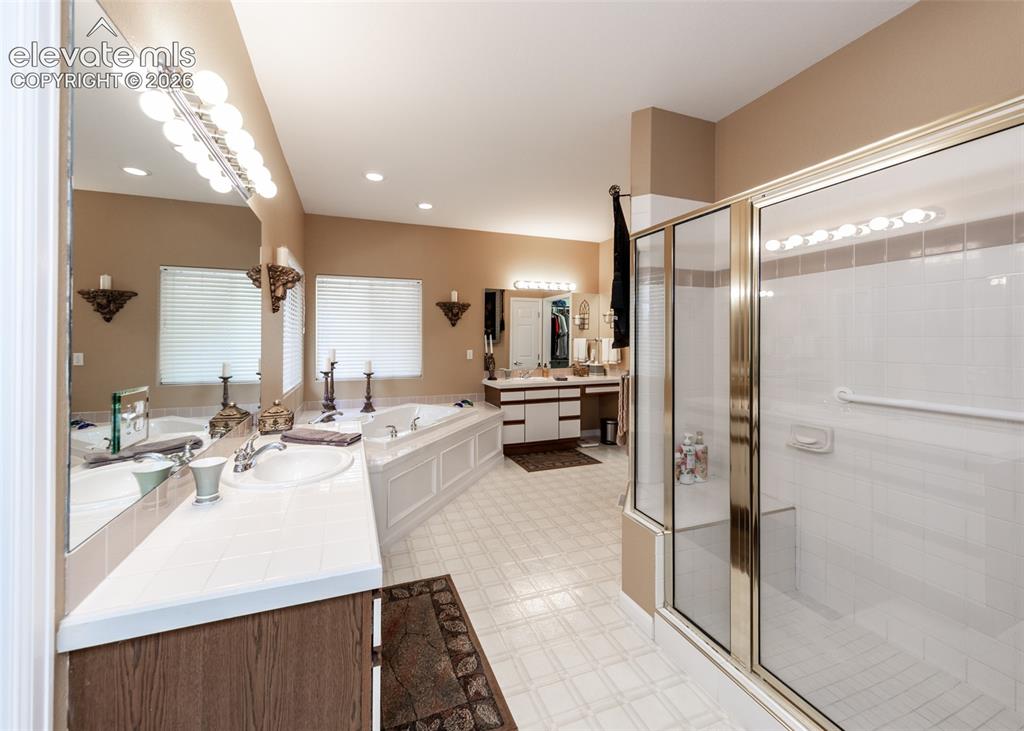 Image 25 of 50: Spacious bathroom featuring a large soaking tub with paneling, dual vanitie