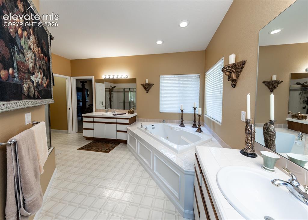 Image 26 of 50: Spacious bathroom featuring a built-in jetted tub, dual vanity with undermo