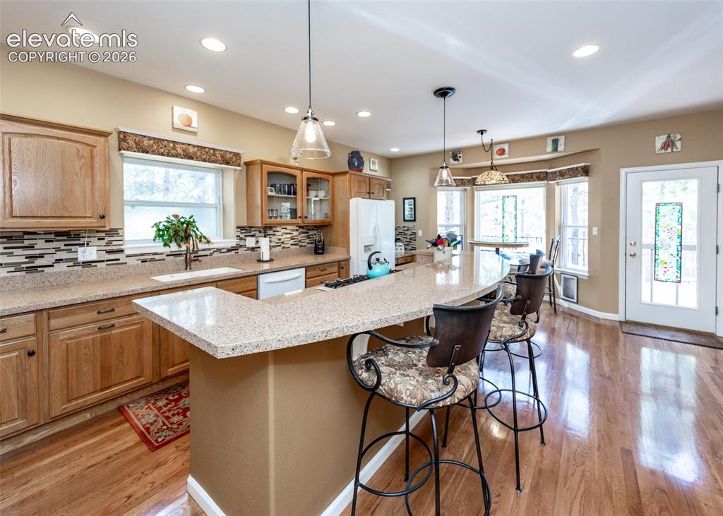 Image 29 of 50: Kitchen featuring a curved peninsula island with seating, a mosaic tile bac