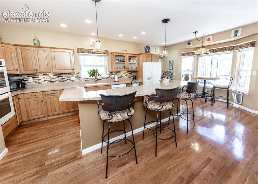 Image 30 of 50: Kitchen featuring wood-finish flooring, a central island with countertop se