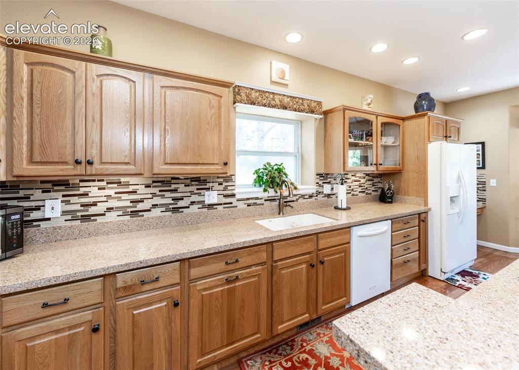 Image 31 of 50: Kitchen featuring light wood cabinetry with black hardware, a multi-tone li