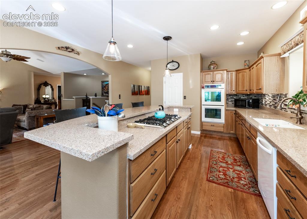 Image 32 of 50: Kitchen featuring light wood cabinetry, recessed lighting, and stone counte