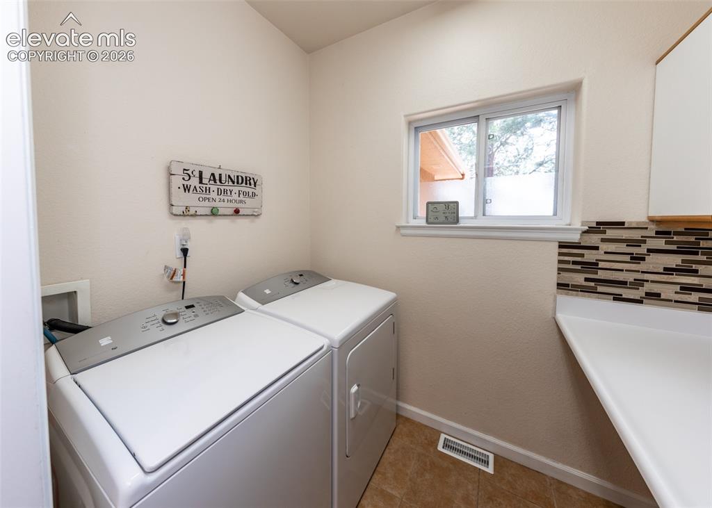 Image 37 of 50: Dedicated laundry area featuring a white countertop, mosaic tile backsplash