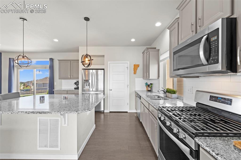 Image 10 of 30: Kitchen with appliances with stainless steel finishes, a breakfast bar area