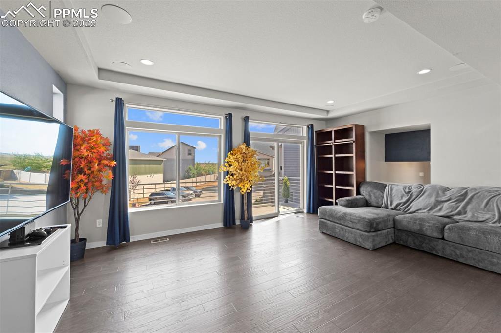Image 11 of 30: Living room with a raised ceiling, wood finished floors, and recessed light