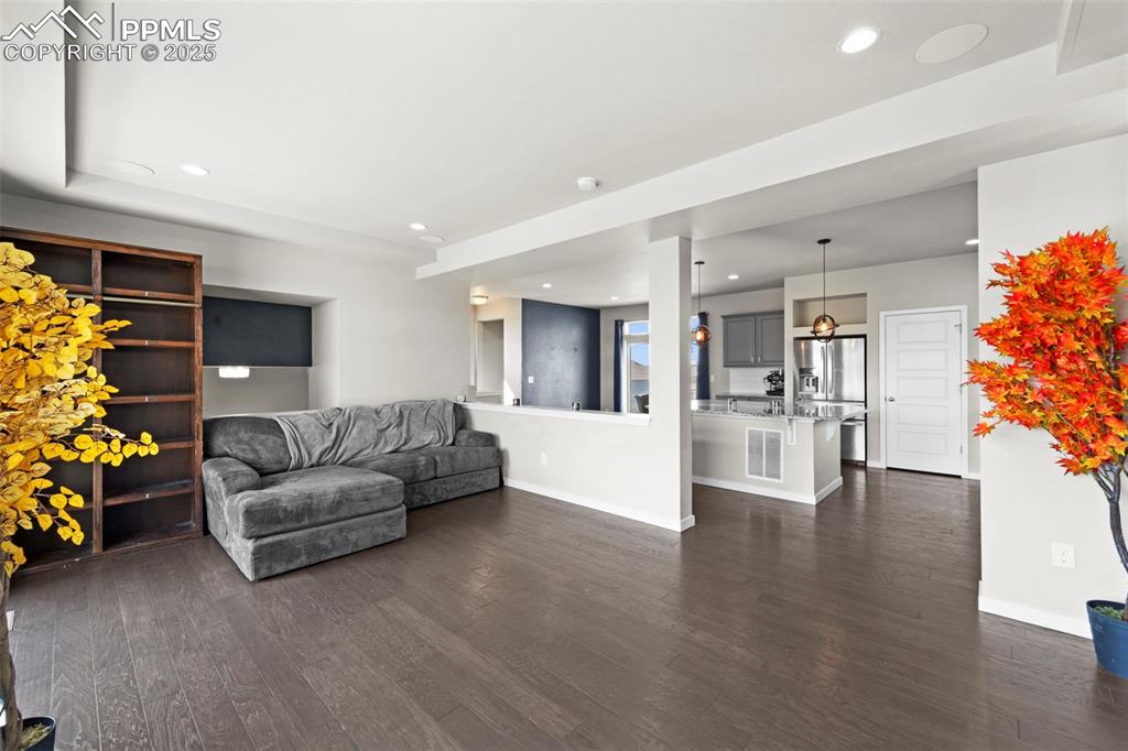 Image 13 of 30: Living area with dark wood-style flooring and recessed lighting