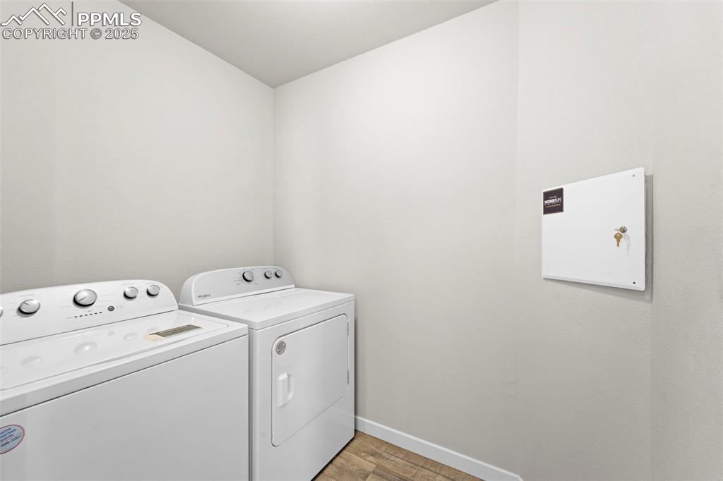Image 19 of 30: Laundry area with wood finished floors and washer and dryer