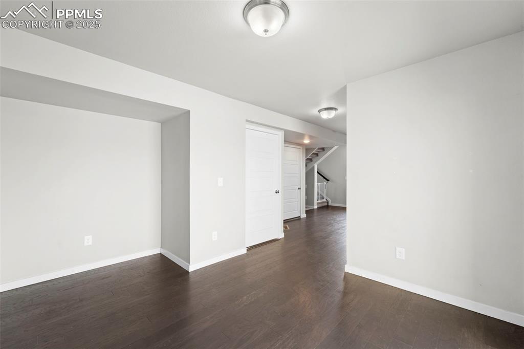 Image 27 of 30: Empty room featuring dark wood-type flooring and stairs