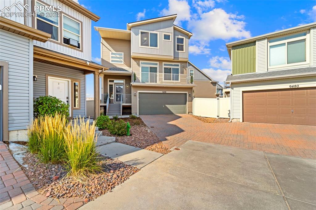 Image 3 of 30: View of front facade with decorative driveway, a garage, and a residential 