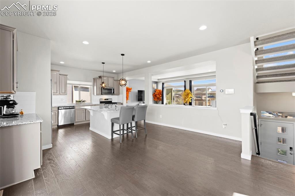 Image 6 of 30: Kitchen with light stone counters, hanging light fixtures, recessed lightin